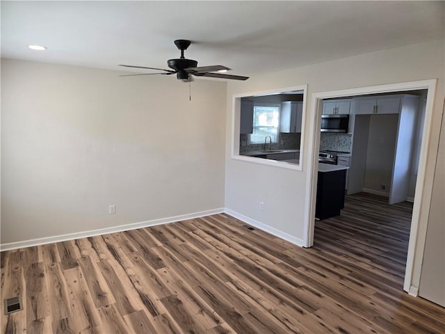 spare room with recessed lighting, a sink, a ceiling fan, baseboards, and dark wood finished floors