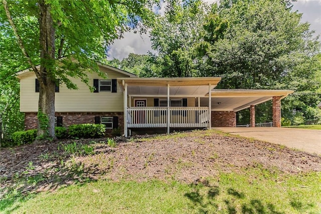tri-level home with brick siding, driveway, covered porch, and an attached carport