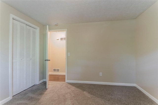unfurnished bedroom featuring carpet, baseboards, a closet, and a textured ceiling