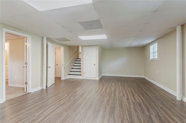 basement featuring stairs, wood finished floors, a drop ceiling, and baseboards