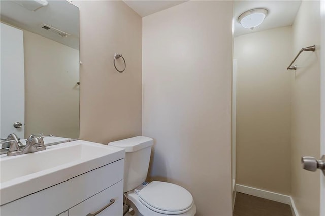 bathroom featuring toilet, baseboards, and vanity