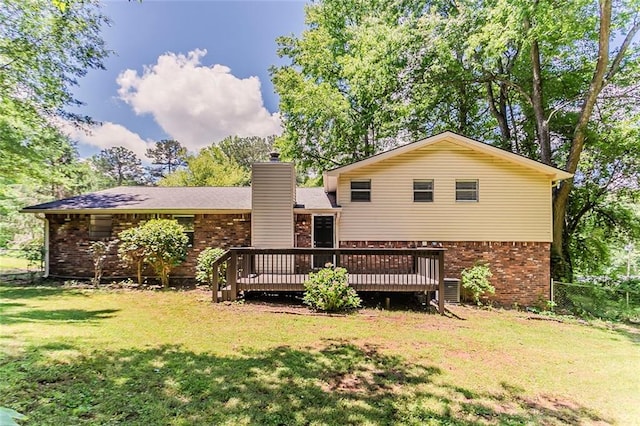 rear view of house featuring brick siding, a wooden deck, and a yard