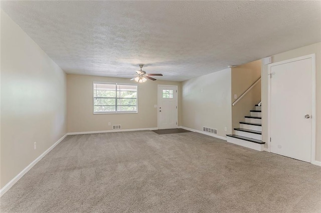 unfurnished living room with a textured ceiling, ceiling fan, stairway, carpet flooring, and baseboards
