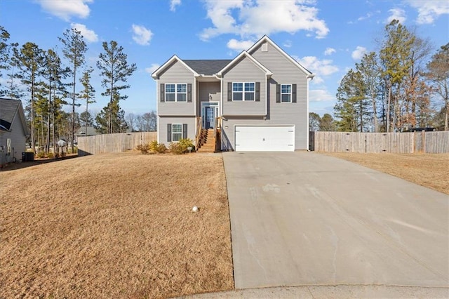 raised ranch with a garage, driveway, and fence