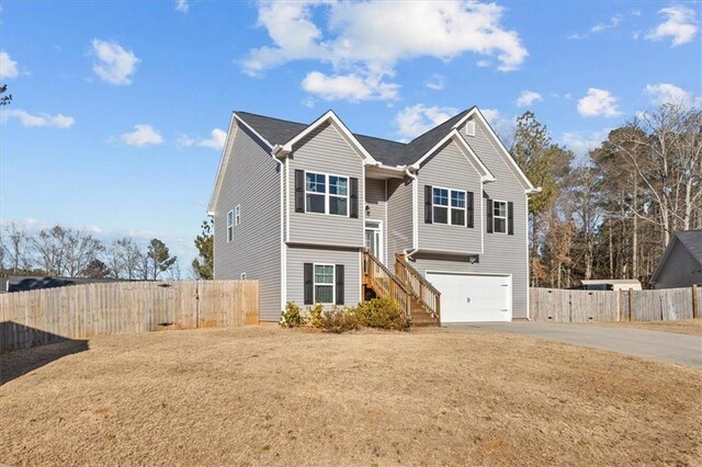 view of front of property featuring an attached garage, fence, a front lawn, and concrete driveway