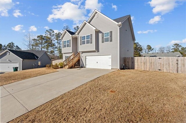 view of front of property featuring driveway, a garage, stairs, fence, and a front lawn