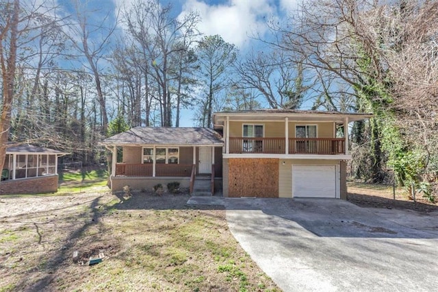 split level home featuring a garage, covered porch, driveway, and a sunroom