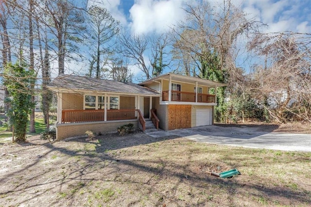 split level home with an attached garage, covered porch, concrete driveway, and brick siding