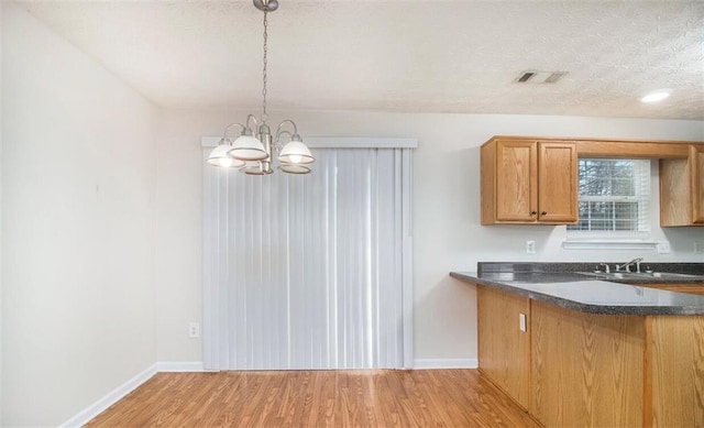2960 Fields Dr, Lithonia, GA 30038 - kitchen with dark countertops, light wood finished floors, baseboards, a chandelier, and brown cabinetry