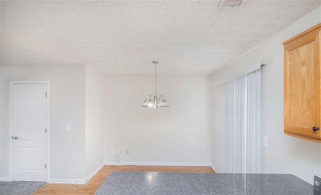 2960 Fields Dr, Lithonia, GA 30038 - unfurnished dining area with a chandelier, baseboards, a textured ceiling, and light wood-type flooring