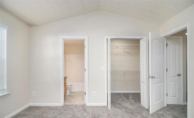 2960 Fields Dr, Lithonia, GA 30038 - unfurnished bedroom featuring a walk in closet, carpet floors, a closet, vaulted ceiling, and connected bathroom