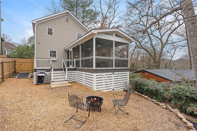 rear view of house featuring ceiling fan, a sunroom, and a fire pit