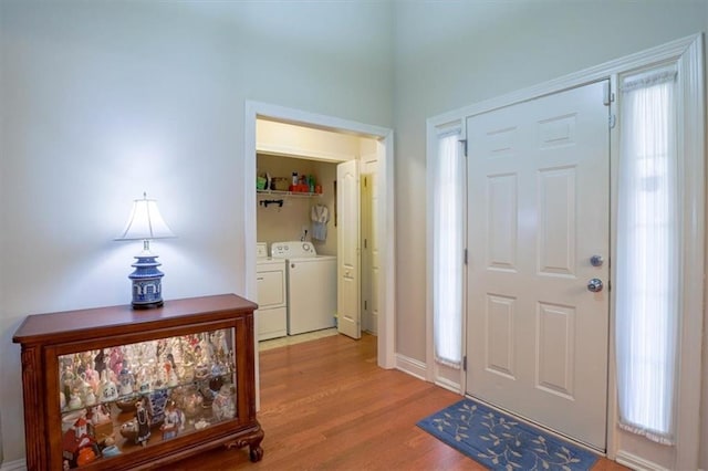 foyer with light wood-style floors, baseboards, and washer and dryer