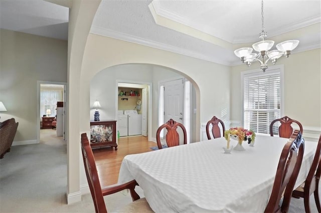 dining space featuring washing machine and dryer, arched walkways, crown molding, and a chandelier