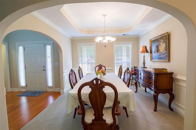 dining space featuring a chandelier, arched walkways, crown molding, and light colored carpet
