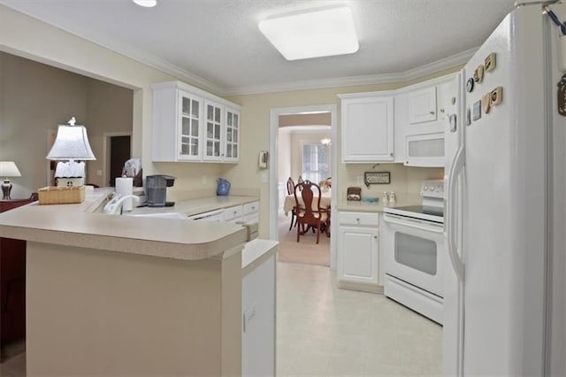 kitchen featuring a peninsula, a sink, glass insert cabinets, white appliances, and light countertops