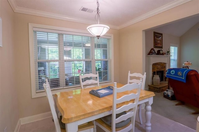 dining space featuring a fireplace with raised hearth, visible vents, crown molding, and baseboards