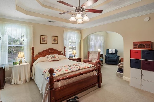 bedroom featuring light colored carpet, arched walkways, and a raised ceiling
