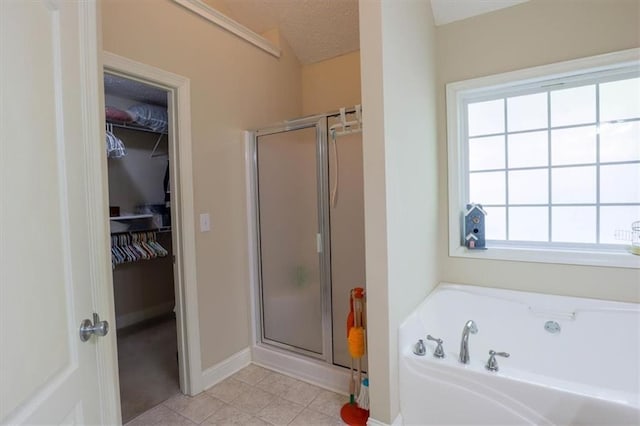 bathroom featuring a walk in closet, a garden tub, and a stall shower