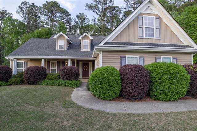 view of front of house with board and batten siding, a shingled roof, and a front yard
