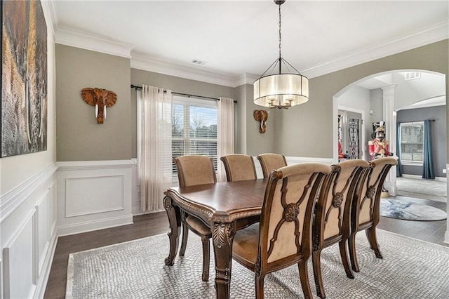 dining area featuring dark wood-type flooring, ornamental molding, and decorative columns