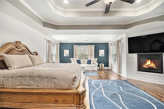 bedroom featuring crown molding, hardwood / wood-style flooring, a raised ceiling, and ceiling fan