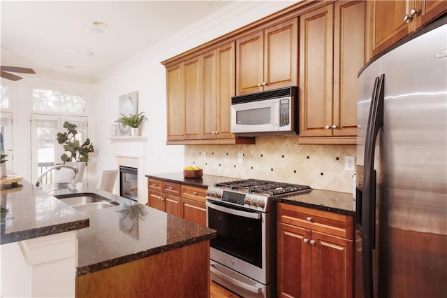 kitchen featuring ornamental molding, a sink, tasteful backsplash, stainless steel appliances, and dark stone counters