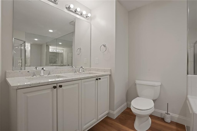 bathroom featuring a tub to relax in, toilet, vanity, and hardwood / wood-style flooring