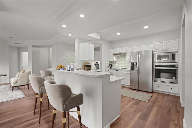 kitchen featuring stainless steel appliances, light hardwood / wood-style flooring, backsplash, kitchen peninsula, and white cabinets