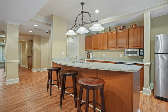 kitchen featuring pendant lighting, light wood-type flooring, stainless steel appliances, and light stone counters