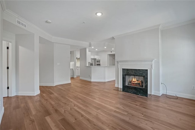 unfurnished living room with light hardwood / wood-style floors, ornamental molding, and a fireplace