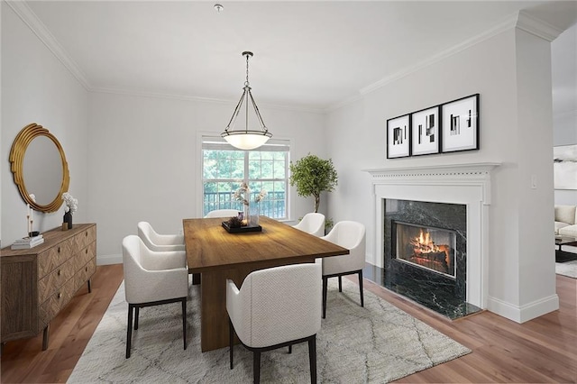 dining space featuring a fireplace, crown molding, and light hardwood / wood-style flooring