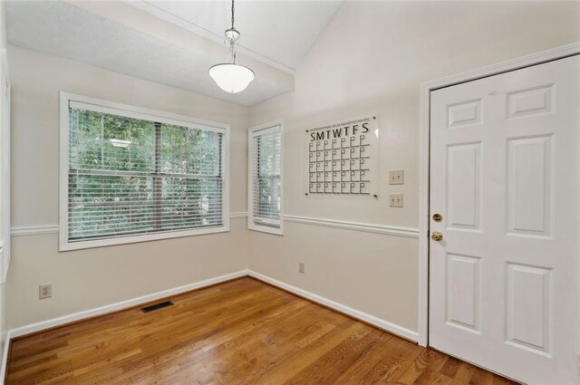 spare room featuring wood-type flooring and lofted ceiling