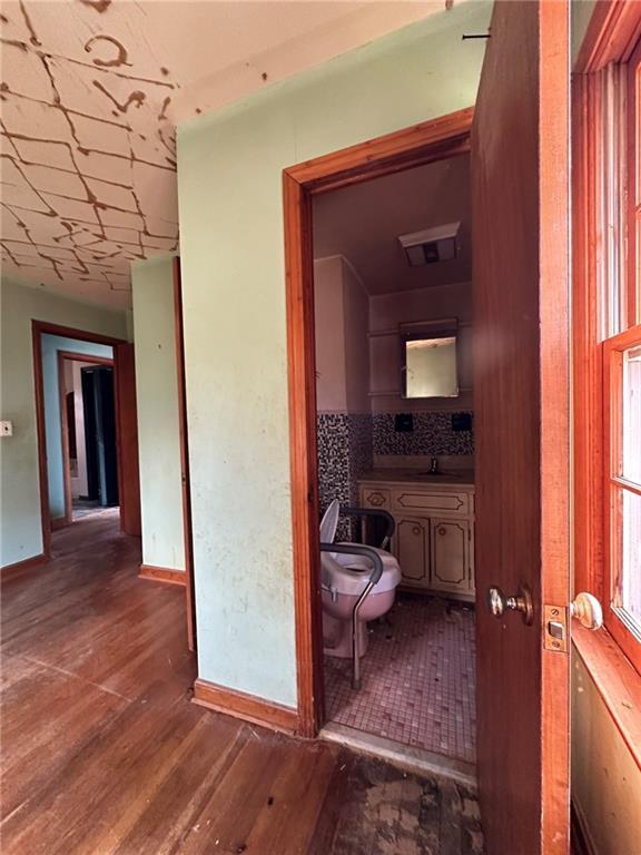 hallway featuring a sink, wood finished floors, and baseboards