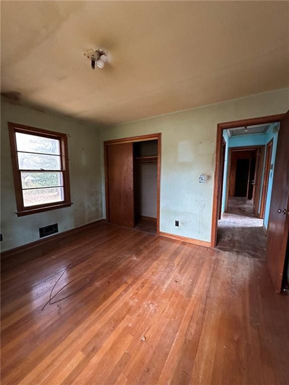 unfurnished bedroom with a closet, light wood-type flooring, visible vents, and baseboards