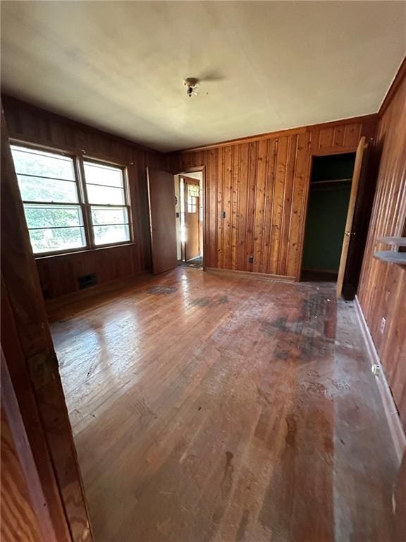 unfurnished bedroom with wooden walls, visible vents, and hardwood / wood-style floors