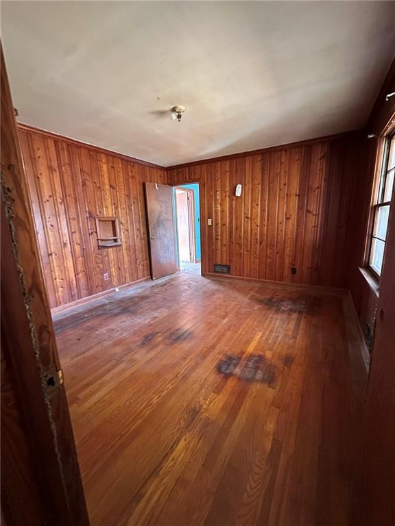 unfurnished room with wood walls, baseboards, and hardwood / wood-style flooring