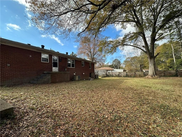 view of yard featuring central AC and fence