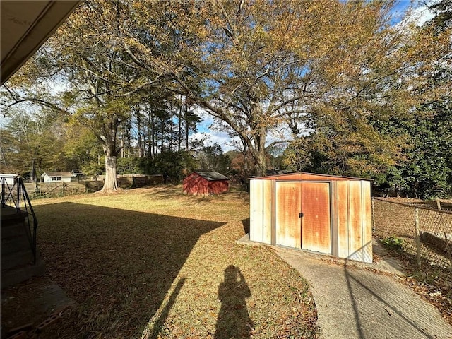 view of yard with a storage shed, an outdoor structure, and fence