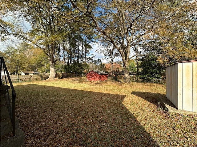 view of yard featuring a storage unit, an outdoor structure, and fence