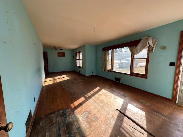 unfurnished living room featuring wood-type flooring, visible vents, and baseboards