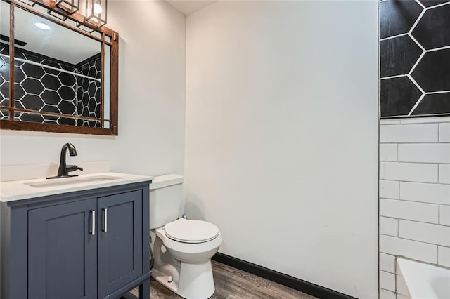 bathroom featuring a bathtub, hardwood / wood-style floors, toilet, and vanity