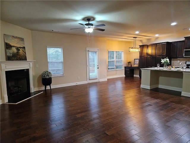 unfurnished living room featuring dark hardwood / wood-style floors and ceiling fan