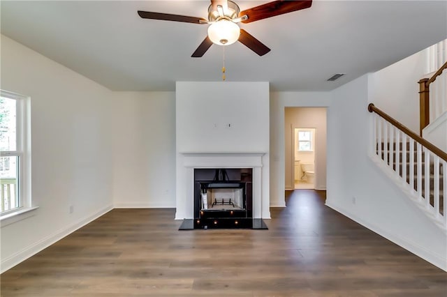 unfurnished living room with ceiling fan, a fireplace, wood finished floors, and visible vents