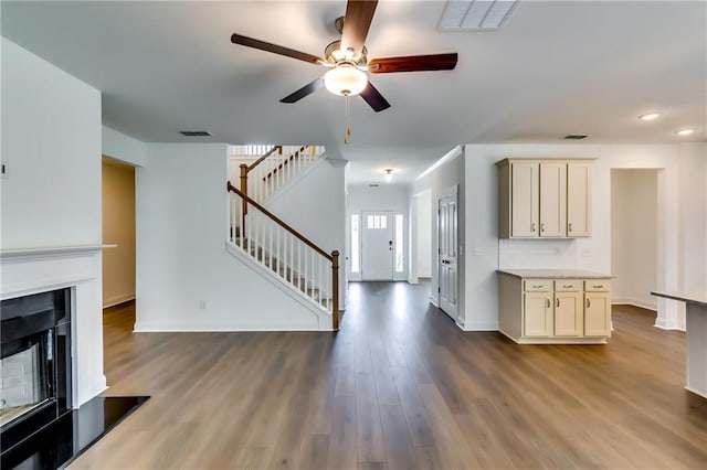 unfurnished living room featuring baseboards, ceiling fan, stairs, and visible vents