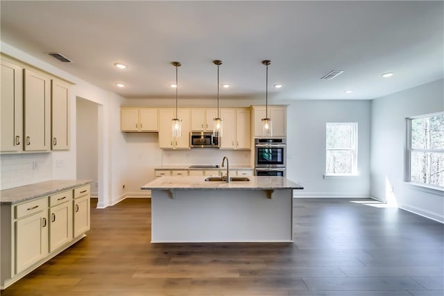 kitchen featuring dark wood-style flooring, stainless steel appliances, visible vents, and a sink