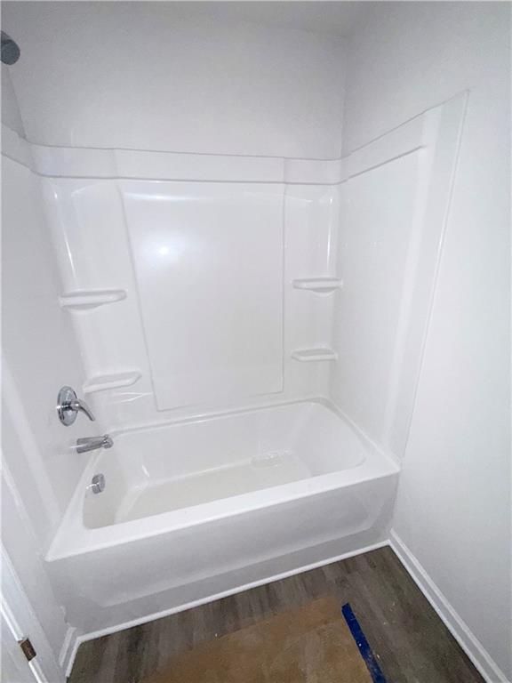 bathroom with baseboards, shower / tub combination, and wood finished floors