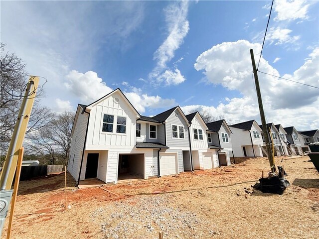 view of front of property featuring a residential view, fence, board and batten siding, and a garage