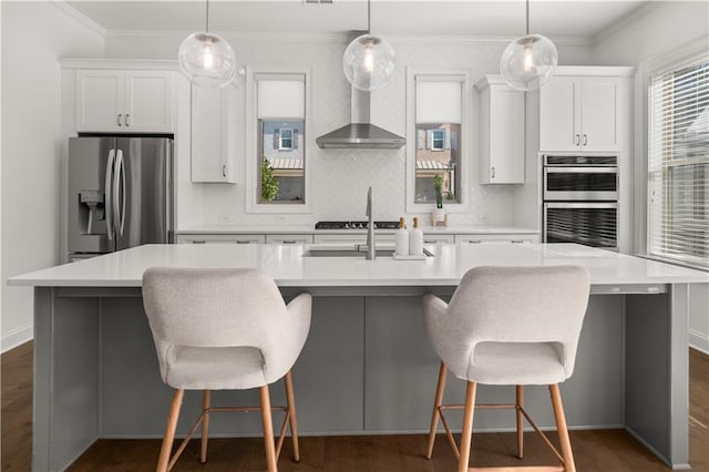 kitchen with white cabinetry, stainless steel appliances, a large island, and wall chimney exhaust hood