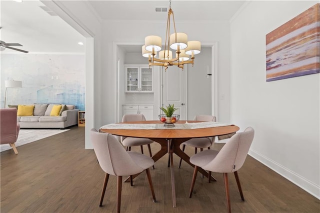 dining room featuring ceiling fan with notable chandelier, dark wood-type flooring, and ornamental molding